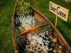 a wooden boat filled with beer bottles on top of a lush green field next to a sign that says deer dance