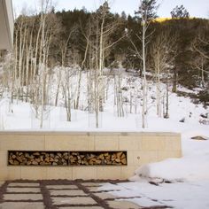 a fire place sitting in the middle of a snow covered field next to a forest