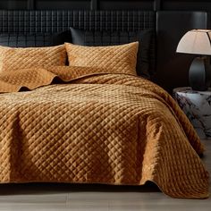 a bed covered in a brown quilt and pillows