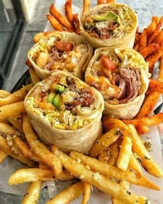 several burritos and french fries on a plate