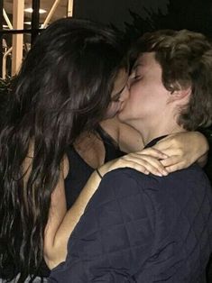 two people are kissing each other outside at night