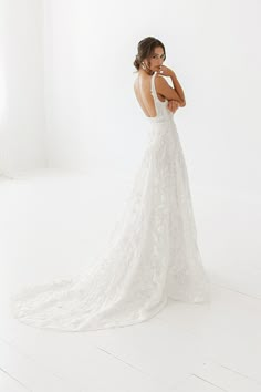 a woman in a white wedding dress is posing for the camera with her back to the camera