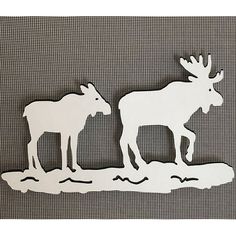 two moose standing next to each other on top of a piece of paper that is cut out