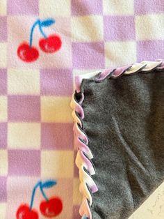 a piece of cloth with cherries on it next to a notebook and pen sitting on a checkered tablecloth