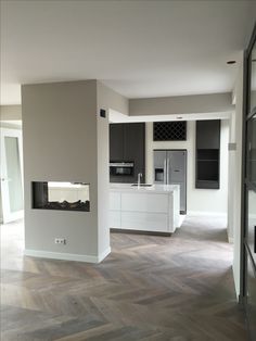 an empty kitchen and living room with wood flooring in the middle of the room