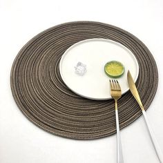 a white plate topped with a fork and knife next to a slice of lemon on top of a place mat