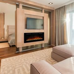 a living room with a couch, television and fireplace in the middle of it's wall