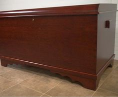 a large wooden chest sitting on top of a tile floor next to a white wall