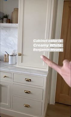 a kitchen with white cabinets and gold handles