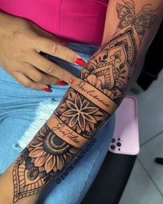 a woman's arm with an intricate tattoo design on her left arm and wrist