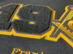 Black and gold sweatshirt Black Varsity T-shirt For Fall, Black Varsity Crew Neck Sweater, Black Top With Letter Embroidery For Streetwear, Black Varsity Tops With Embroidered Logo, Black Varsity Sweater For College, Varsity Black Sweatshirt With Embroidered Logo, Black College Hoodie With Embroidered Logo, Black Sweater With Embroidered Graphics For Streetwear, Black Crew Neck Sweater For College