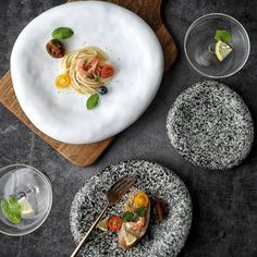 a plate with pasta and vegetables on it next to other plates, glasses and utensils