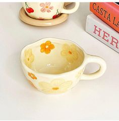 a cup and saucer sitting on a table next to some books with flowers painted on them