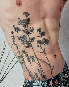 a man's back with flowers and leaves on his stomach, as well as the lower part of his body