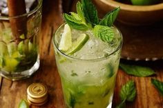 a glass filled with ice and limeade next to some minty garnish