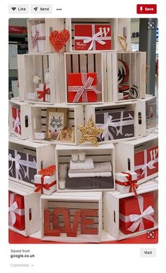 a christmas tree made out of crates and wrapped in red, white and grey paper