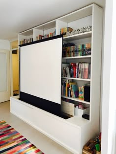 a large screen mounted to the side of a wall in a living room next to a rug