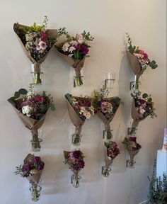 a bunch of flowers are hanging on the wall next to vases with wine glasses