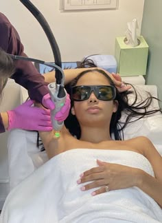 a woman laying in a hospital bed getting her hair brushed