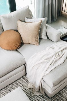 a white couch with pillows on it in front of a window