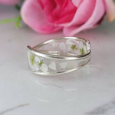 Flowers silver ring meticulously crafted using hand picked flowers and fully cured UV resin. The white silver band is inspired by the graceful charm of Boho jewelry. This Boho band ring is a perfect meaningful gift for a beloved woman, and as a pampering gift for yourself. The jewelry is very flattering, lightweight, comfortable to wear as jewelry for everyday use and impressive as jewelry for a special occasion. Each piece is individually crafted to order, ensuring a unique touch, with subtle variations that make every piece truly one-of-a-kind. Elevate your style with this exceptional jewelry- a wearable piece of art designed for your enjoyment. Purchase now for an exquisite blend of nature and craftsmanship. Special Features: - Handmade with Natural white Lobularia flowers, fully cured Silver Wedding Jewelry With Birth Flower Detail, Wedding Silver Jewelry With Pressed Flowers, Handmade Flower Open Ring For Wedding, Handmade Open Flower Ring For Wedding, Delicate Silver Flower Ring With Round Shape, Delicate Handmade White Rings, Wedding Jewelry With Pressed Flowers In Silver, Silver Wedding Jewelry With Pressed Flowers, Unique White Flower Ring