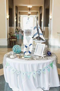 a table with a sailboat on it and decorations around the table for an ocean themed baby shower