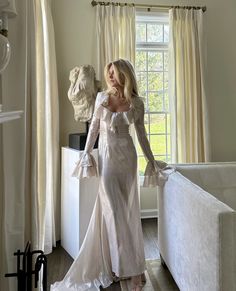 a woman in a white dress standing next to a couch