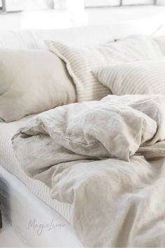 an unmade bed with white sheets and pillows