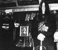 a man sitting on top of a luggage bag in a room filled with posters and other items