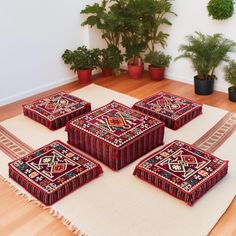 four red and white boxes sitting on top of a rug next to potted plants