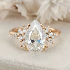 an engagement ring with a pear shaped diamond surrounded by smaller diamonds