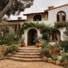 a white house with lots of plants on the front and stairs leading up to it