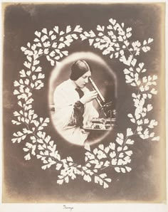 an old photo of a woman holding a book in her hands and surrounded by leaves