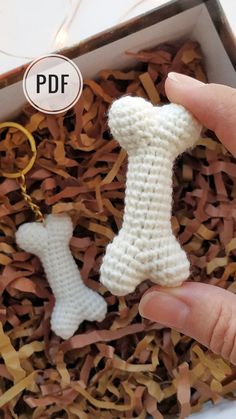 a hand holding a crocheted dog bone and keychain in a box