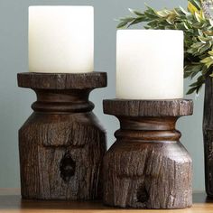 two white candles sitting on top of a wooden table