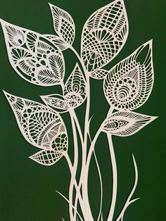 an intricately designed piece of paper art with leaves and flowers in white on a green background