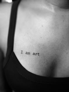 a woman with a tattoo on her chest that says i am art in black and white