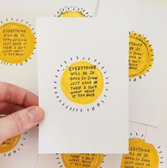 a person holding up some yellow stickers on white paper with words written in them