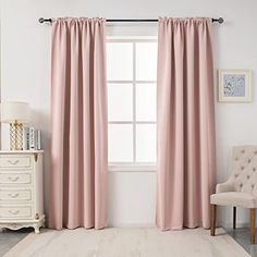 a living room with pink curtains and a white chair in front of a large window