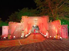 an outdoor wedding venue decorated with pink and white flowers, lit up by candle lights