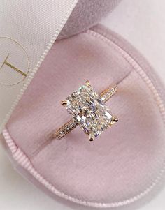 an engagement ring with a cushion - cut diamond in the center on a pink velvet case