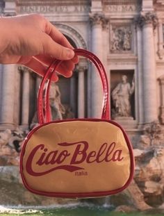 a hand is holding a bag with the word ciabella on it in front of a fountain