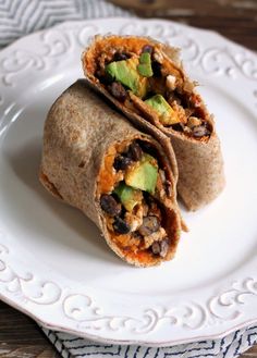 two burritos are sitting on a plate with avocado and black beans