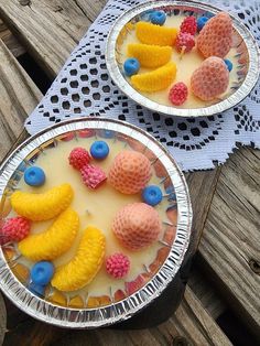 two tin plates filled with fruit on top of a wooden table