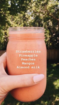 a hand holding a jar of strawberry pineapple peaches and almond milk with the words, strawberries pineapple peaches mangos almond milk