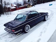 a black car parked on the side of a snow covered road