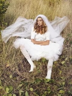 a woman in a wedding dress sitting on the ground