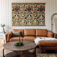 a living room filled with furniture and a large tapestry hanging on the wall above it