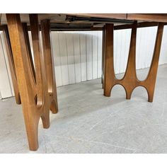 two wooden tables sitting next to each other on top of a white tile floor in front of a wall