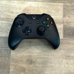 a black controller sitting on top of a wooden floor